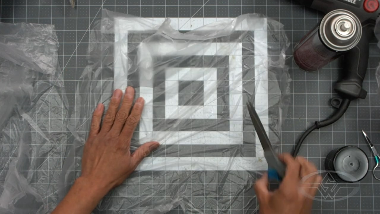 Fraleigh cuts a single, large plastic bag into smaller pieces with torn edges.