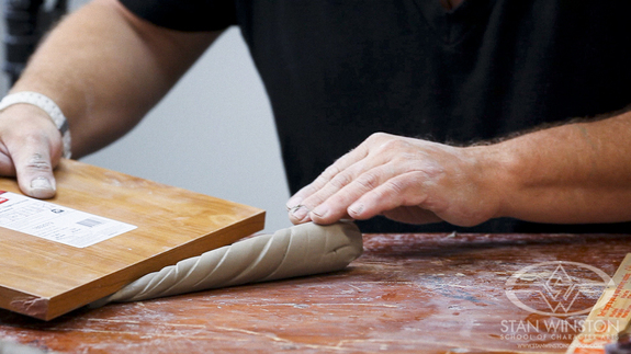 A wooden board transforms a cone of clay into a truly organic-seeming horn.