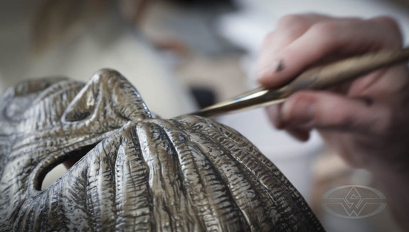 Mitchell applies a wash to his mask infused with a metallic bronze powder.