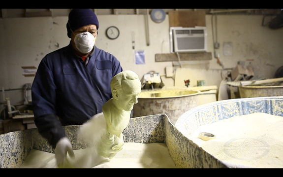 AFAF's Enrique sifts a fine sand coat onto the hollow wax casting after it has been dipped in a slurry.