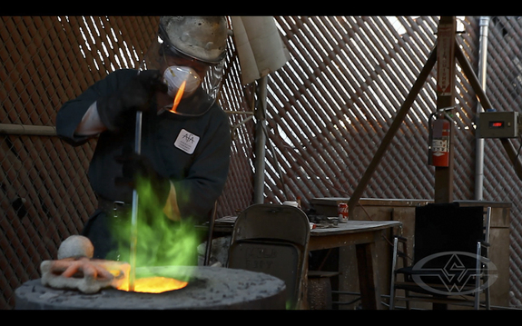 Before the pour, the crew removes the slag from the surface of the molten bronze.